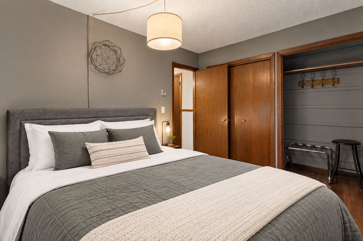 Bedroom with an upholstered gray headboard, a gray quilt, and a cream knit throw